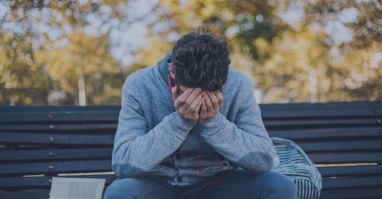 man hunched over bench sad