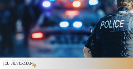 Police officer outside a police cruiser with its lights on