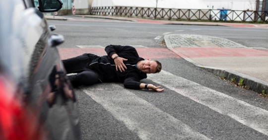 man hit by car, lying down on the road