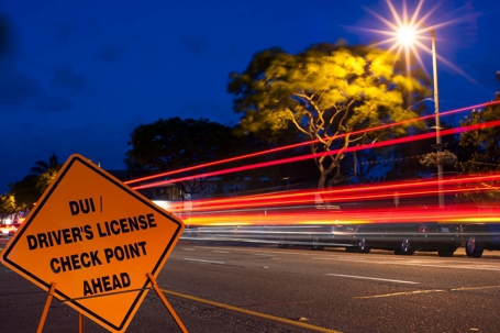 Blurry car lights at night with DUI check point sign